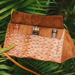 A stunning handmade leather watch roll displaying three watches outdoors, showcasing craftsmanship and style.