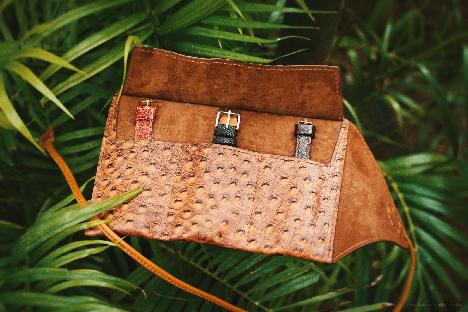 A stunning handmade leather watch roll displaying three watches outdoors, showcasing craftsmanship and style.